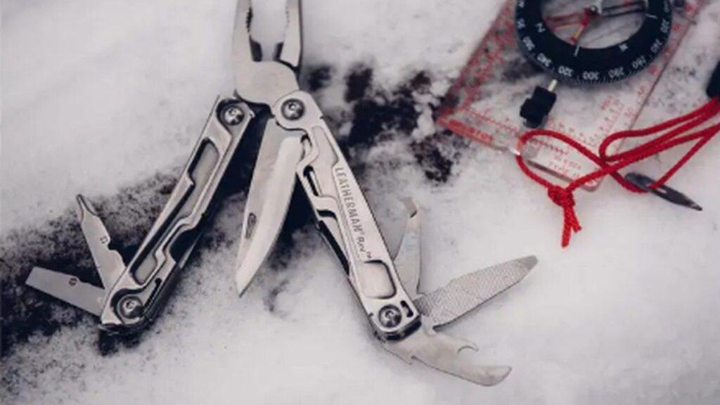 Multi-tool on snow beside a compass for practical everyday preparedness and repairs
