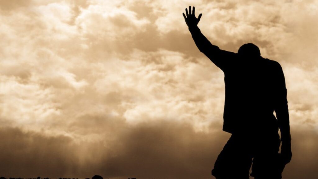 Person praying with arm raised toward heaven
